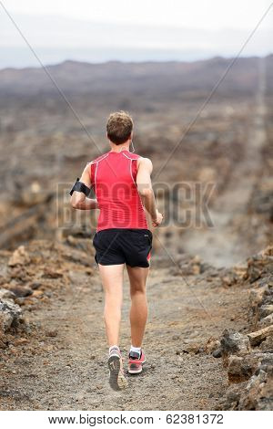 Trail runner man running cross-country run training outside for marathon. Jogging male athlete working out as part of healthy lifestyle. Rear view showing back from behind on Big Island, Hawaii, USA.