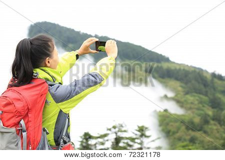 woman hiker taking photo with cell phone at peak of emei mountain ,china