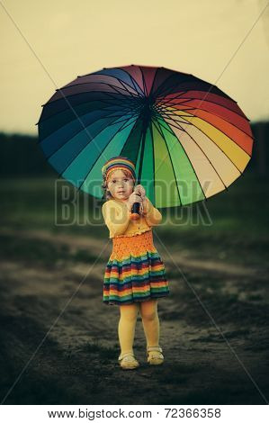 little girl with rainbow umrella in the field