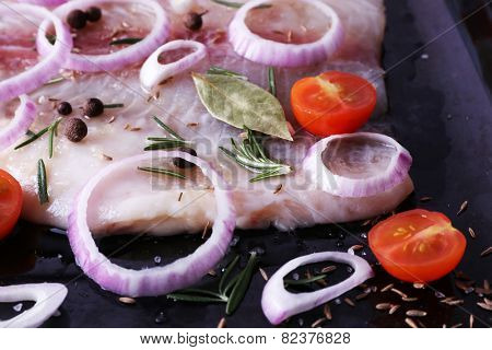 Pangasius fillet with spices and vegetables on firepan background