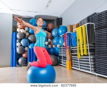 Girl at gym swiss ball knee balance drill exercise workout open arms