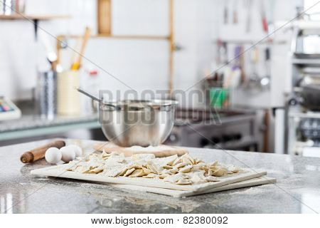 Unprepared ravioli pasta on cutting board with ingredients at countertop in commercial kitchen