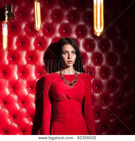 young woman in red dress standing near wall