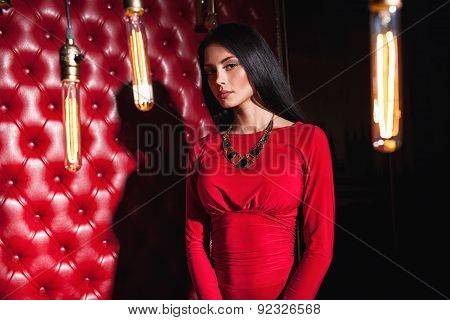 young woman in red dress standing near wall