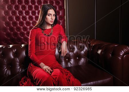 young woman in red dress sitting on leather sofa
