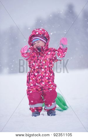 happy family on winter vacation, mom and cute little girl have fun and slide while snow falkes falling
