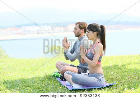 Couple doing meditation and yoga exercises in outdoor park