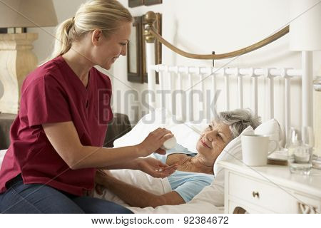 Health Visitor Giving Senior Woman Medication In Bed At Home