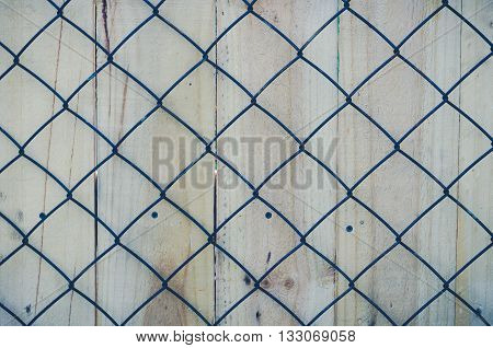 Metal mesh for fencing. Closeup on the background of wooden boards.