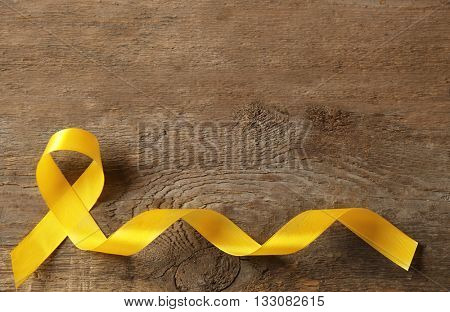 Yellow awareness ribbon on wooden background