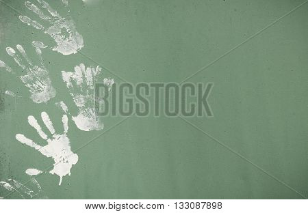 White paint hand print on green metal wall texture.