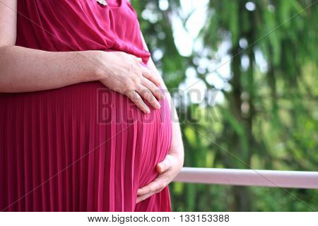 Pregnant woman expecting child, hands on the belly