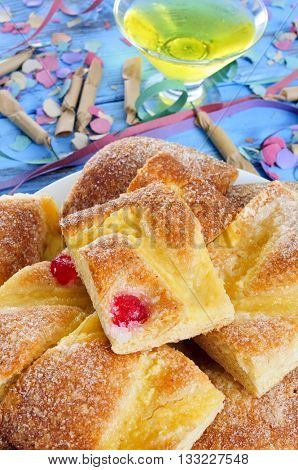 a plate with pieces of coca de Sant Joan, a typical sweet flat cake from Catalonia, Spain, eaten on Saint Johns Eve, on a rustic blue table, with champagne, firecrackers, confetti and streamers