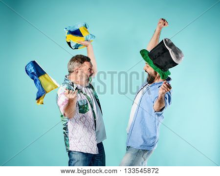 The two football fans with a flag of Ukraine over blue background