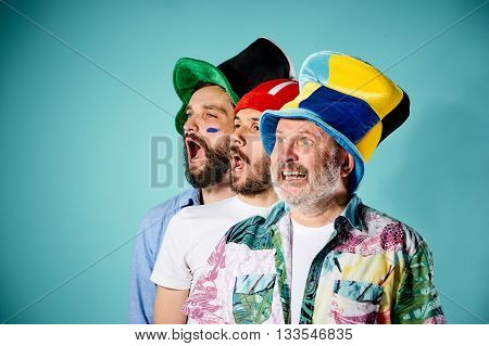 The three football fans singing the national anthem over blue background