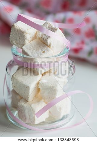 White marshmallows in glass jar on white table