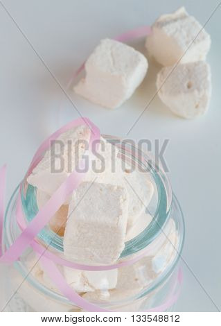 White marshmallows in glass jar on white table