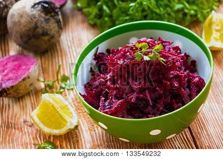 Salad: diet salad with beetroot, olive oil and lemon. Served in a bowl on wooden background. Beetroots, lemon and lettuce on kitchen table.