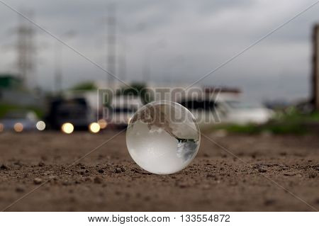 Transparent ball on the roadway. Evening lights of cars. In the bowl of a reflection of the electrical towers. Concepts, ideas - on the roads care. Electricity in the city. Urban ecology, traffic safety. Clean city