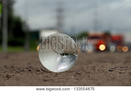 Transparent ball on the roadway. Evening lights of cars. In the bowl of a reflection of the electrical towers. Concepts, ideas - on the roads care. Electricity in the city. Urban ecology, traffic safety. Clean city