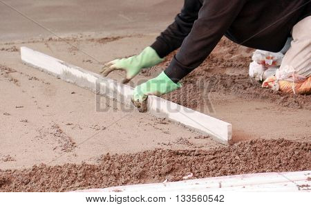 Picture of a Concreting the floor of a house. motion blur on grading tool and hands.