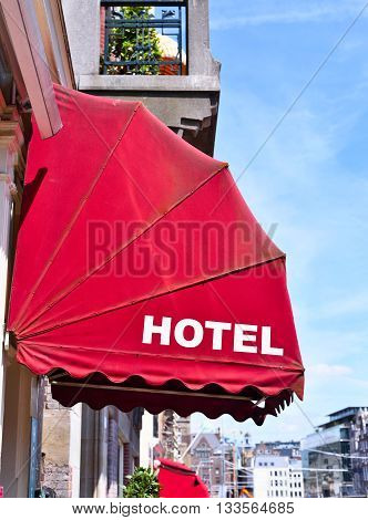 Building exterior of an ancient city hotel with red sun blind and white text. Selective focus with copy space.