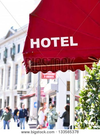 Building exterior of an ancient city hotel with red sun blind and white text. Selective focus with copy space.