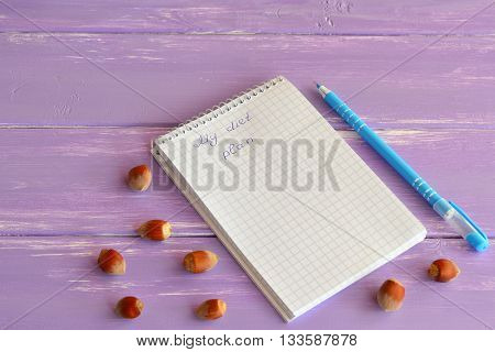 Paper notebook, pen, nuts on lilac wooden background. My diet plan. Slimming concept. Lifestyle. A notepad diet menu. Notepad for diets programs