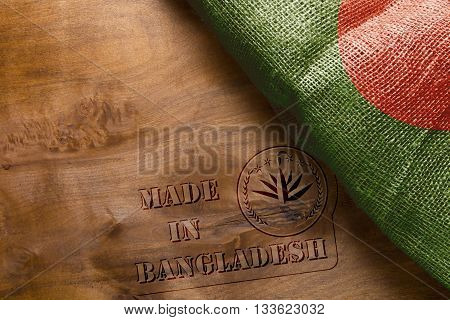 A reprint of the stamp on a wooden surface - Made in Bangladesh with the country's flag.
