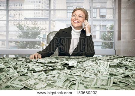 portrait of young woman sitting behind the table full of cash