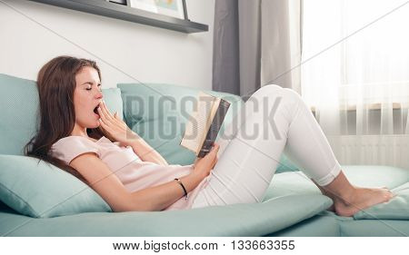 Sleppy Woman Lying On Couch And Reading Boring Book At Home. Casual Style Indoor Shoot