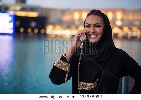 Attractive young arabic woman talking on a mobile phone in the city.
