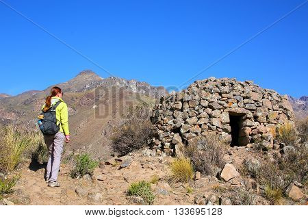 Tourist looking at pre-Incan round house named colca near Chivay in Peru. Colcas are circular stone structures used for food storage or burials.