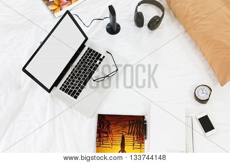 Blank screen laptop or notebook with all things around on bed in background work on bedmusic shopping online connected on bed miscellaneous on bed