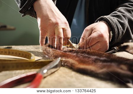 The tailor cuts a template dress leather knife tailoring