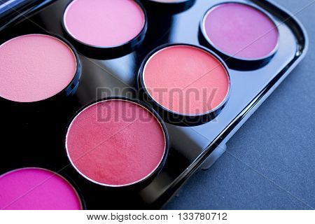 Colorful blush, shadow set on black background. Dry textured palette of professional cosmetics.