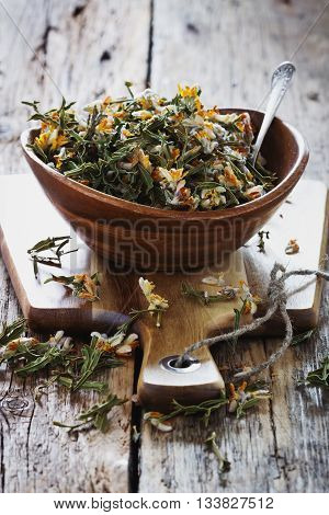 Dried medicinal herbs in a bowl on a wooden table.( Carqueja and Genista Tridentata). Close-up. Alternative treatment . Selective focus