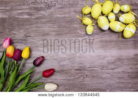 cloth multicolored tulips and tellow easter egg on wood