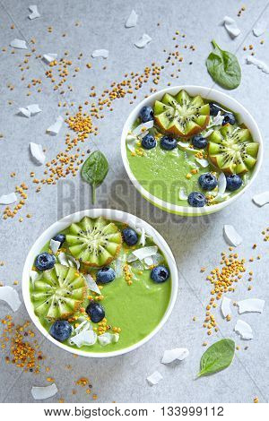 breakfast green smoothie bowl topped with kiwi, blueberry, coconutflake and bee pollen
