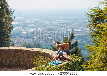 Bergamo, Italy - August 18, 2017: An Unfamiliar Man Is Sunbathing On The Fortress Wall.