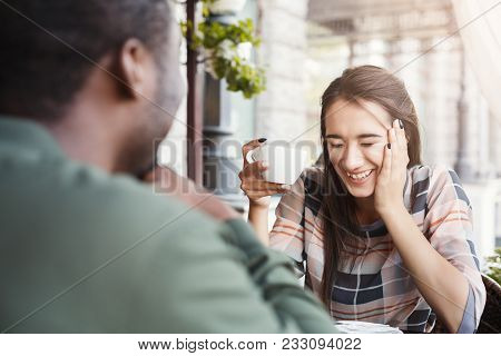 Young Bored Girl Sitting And Using Smartphone On Date With Her Boyfriend At Cafe. Speed Dating, Unsu