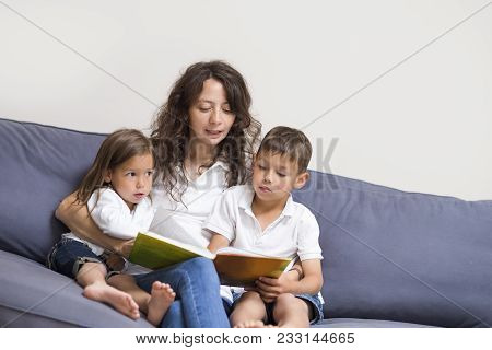 Family Relationships Concepts. Mother Reading A Book Together With Her Children Indoors.horizontal I