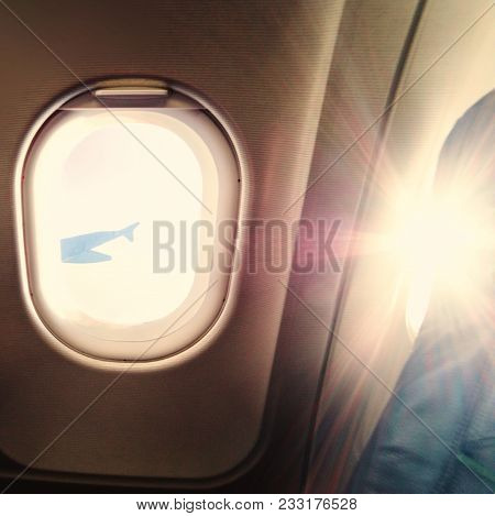 Airplane Window View Inside An Aircraft. Window Plane At Sunrise With Rays Of Morning Light In Vinta
