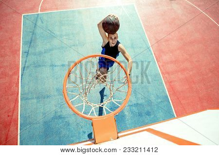 Young Man Jumping And Making A Fantastic Slam Dunk Playing Streetball, Basketball. Urban Authentic