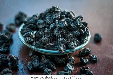 Black Raisin Or Kali Kishmish Or Zante Currant In A White Plate On Wooden Surface In Dark Gothic Col