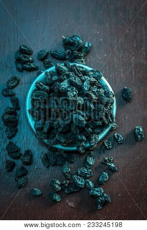 Black Raisin Or Kali Kishmish Or Zante Currant In A White Plate On Wooden Surface In Dark Gothic Col
