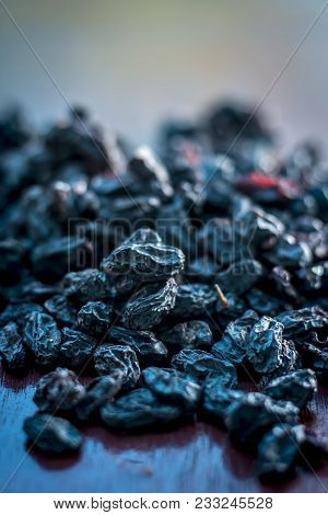 Black Raisin Or Kali Kishmish Or Zante Currant In A White Plate On Wooden Surface In Dark Gothic Col