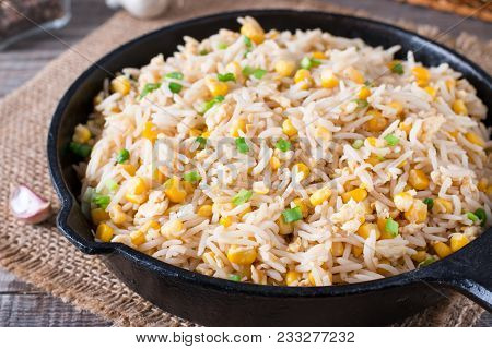 Asian Fried Rice With Eggs And Corn In A Frying Pan On Wooden Table
