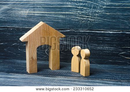 Two People Stand Near The House And Evaluate Its Qualities Before Buying. The Concept Of Buying And 