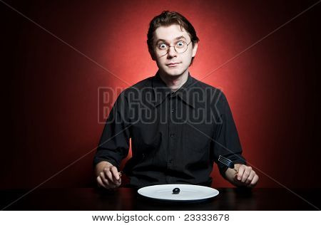 Funny and strange young man eating grape